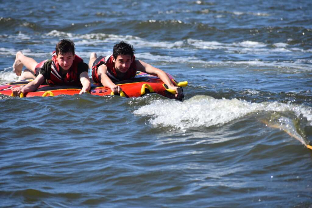 Scouts being pulled behind the boat on a tube